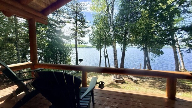 Eine Holzterrasse mit Blick auf einen See und Bäume.