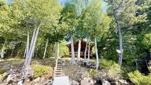 Eine Hütte, umgeben von Bäumen, mit einer Holztreppe.