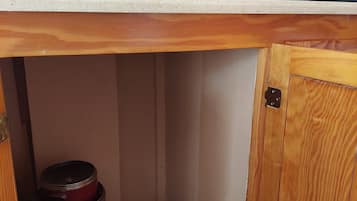 Uma cozinha com bancada, cafeteira, chaleira e panelas empilhadas.