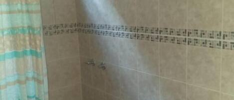 A bathroom with a toilet, shower, and sink.