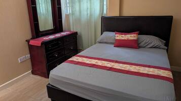 Un dormitorio con cama, cómoda, espejo y ventana con cortinas.