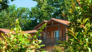 A wooden cabin with a balcony, surrounded by lush greenery. - Apartment in Eauze With Private Pool (Eauze)
