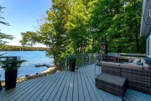 A deck with outdoor furniture overlooking a lake, surrounded by trees. - Casa Albanese on Farlain Lake (Tiny)