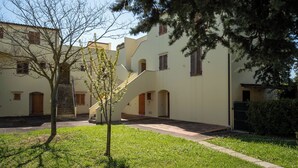 Ein Innenhof mit Treppe, Baum und Gebäude mit zahlreichen Fenstern und Eingängen.