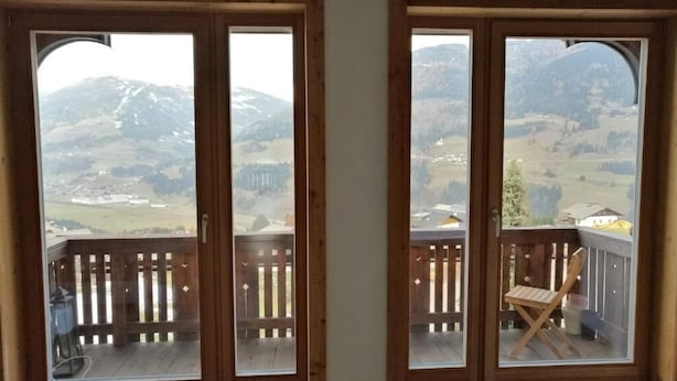 A room with two sliding glass doors leading to a balcony with a wooden railing. - Bella Vista Lodge (Kartitsch)