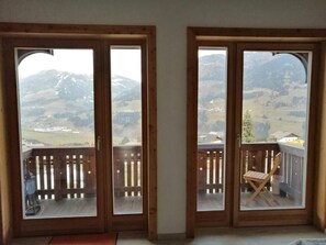 Une pièce dotée de deux portes-fenêtres coulissantes donnant sur un balcon avec une rambarde en bois.
