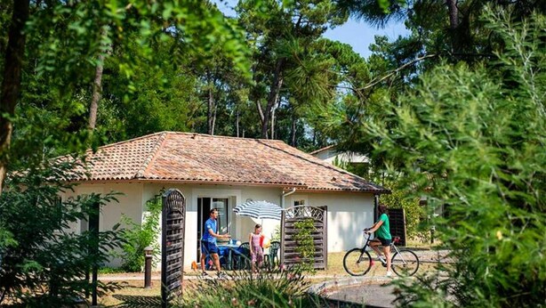 Een klein huis met pannendak, omgeven door bomen.