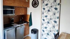 A compact kitchen with wooden cabinets, a microwave, a sink, a dishwasher, and a trash bin. - Les Marmottes Ndeg112 - ST5 (Chamrousse)