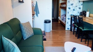 A cozy living room with a green sofa, a small white table, and a bunk bed in the background. - Les Marmottes Ndeg112 - ST5 (Chamrousse)