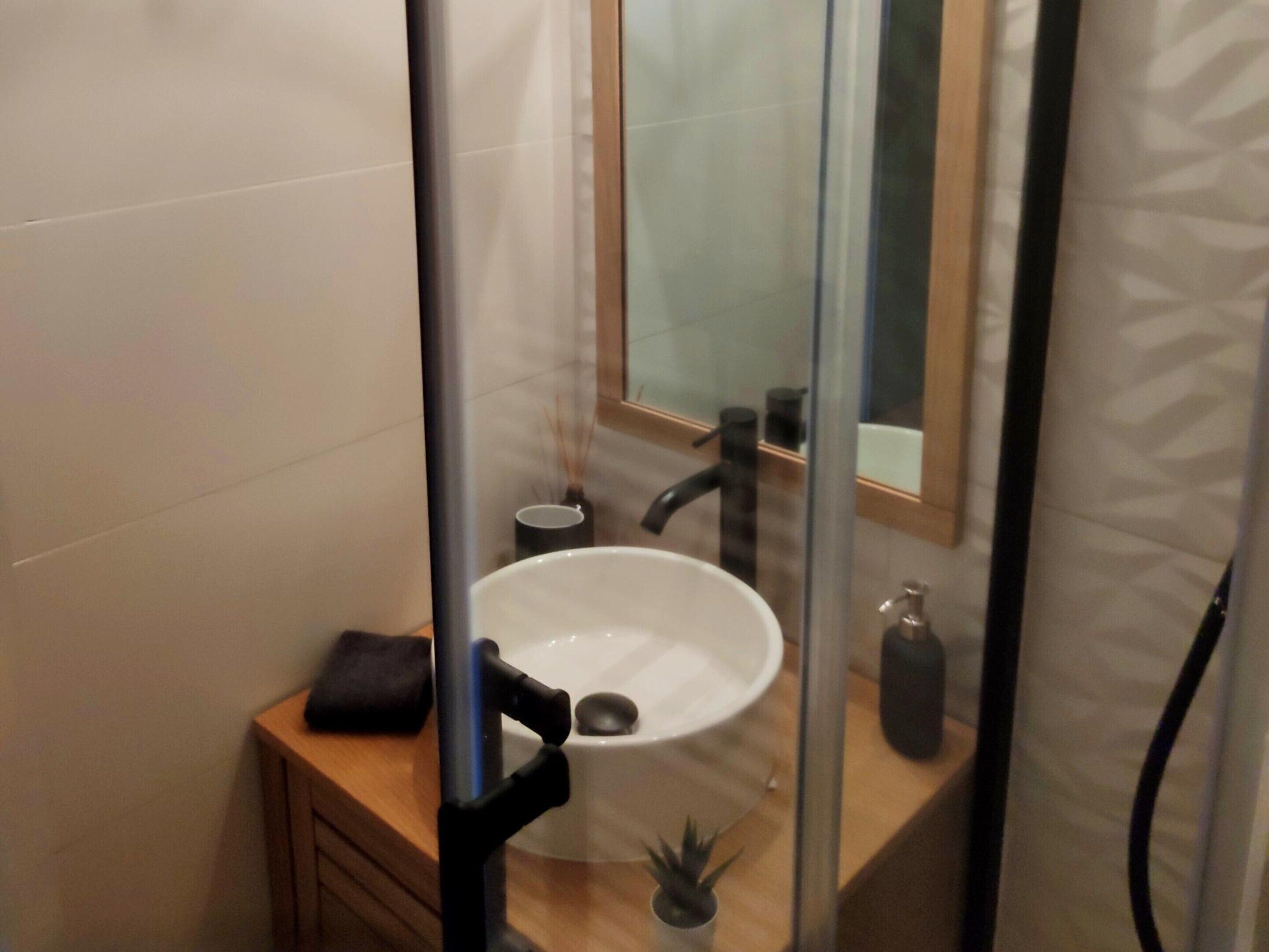 A bathroom with a white sink, a mirror, and a wooden vanity.