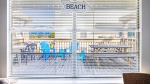 Vista attraverso una finestra con un cartello che indica 'BEACH' e mobili da esterno.