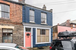 A two-story building with a blue and white facade, a pink door, and a black car parked in front. - Stylish and Central Cottage Home in Montpelier (Bristol)