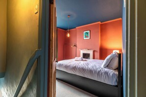 A bedroom with a bed, a fireplace, and a hanging light fixture. - Stylish and Central Cottage Home in Montpelier (Bristol)