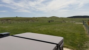 A grassy field with a fence, a hill, and a distant hill.