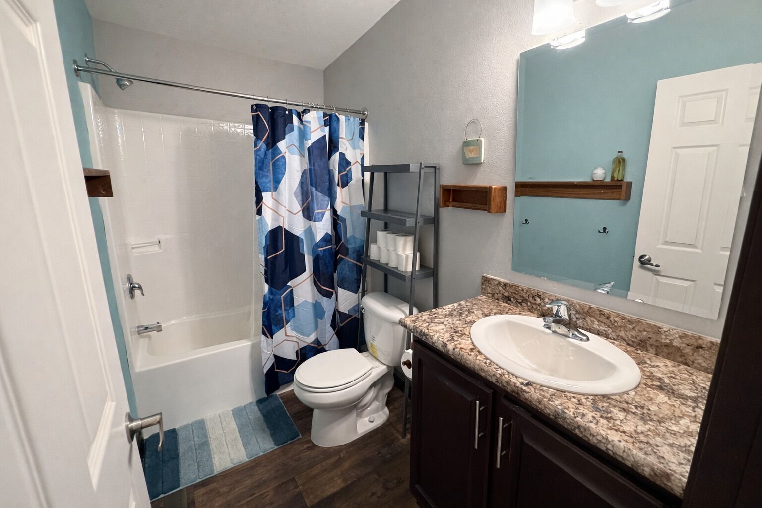 A bathroom with a shower, toilet, sink, and a mirror.