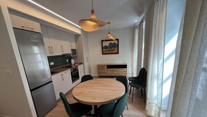 Una cocina moderna con refrigerador, microondas y horno integrados. Hay una mesa de comedor con sillas y una lámpara colgante arriba.