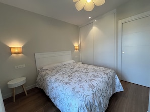 A bedroom with a bed, a bedside table, and two wall-mounted lamps.