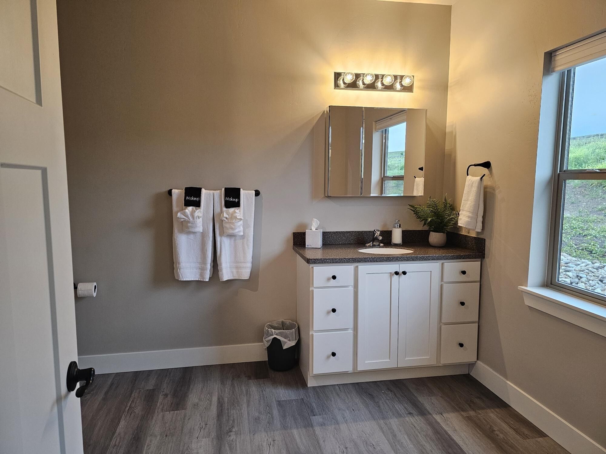 Une salle de bain avec un meuble-lavabo, un miroir, un évier et une fenêtre.
