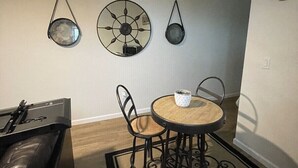 A living room with a sofa, a small round table with two chairs, and decorative wall art.