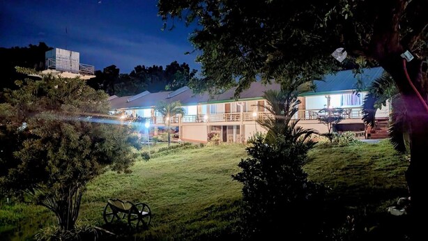 A two-story building with a balcony and a well-lit outdoor area, surrounded by greenery. - Harmony Place (Puerto Princesa)