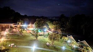A well-lit outdoor area with a pool, seating, and a covered structure, surrounded by greenery. - Harmony Place (Puerto Princesa)