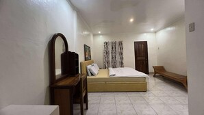 A bedroom with a bed, a desk, a chair, a mirror, a door, and a bench. - Harmony Place (Puerto Princesa)