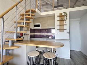 Eine moderne Küche mit einer zentralen Kochinsel, einer eingebauten Mikrowelle und einer Treppe mit Holzhäuschen.