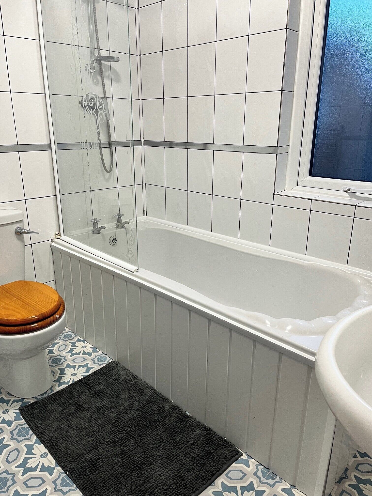 A bathroom with a bathtub, toilet, and a window.
