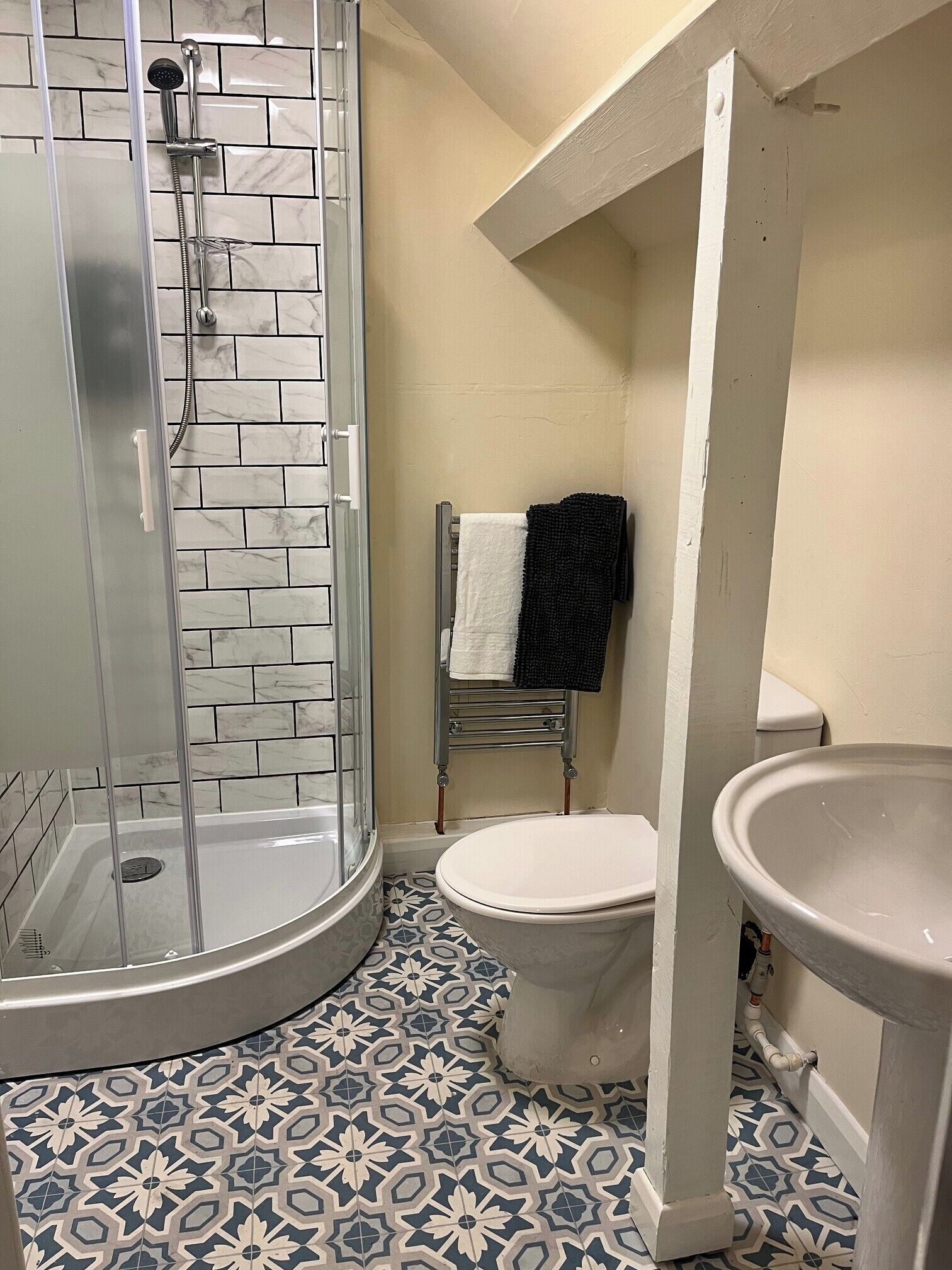 A bathroom with a glass-enclosed shower, a toilet, and a sink.