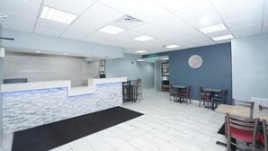 A reception area with a stone counter, several tables and chairs, and a clock on the wall. - Red Carpet Newnan (Newnan)