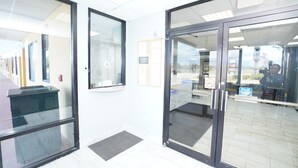 A reception area with glass doors, a reception desk, and a sign indicating a pull station. - Red Carpet Newnan (Newnan)