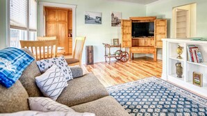 Una sala de estar acogedora con un sofá, una mesa de centro, un televisor y una estantería.