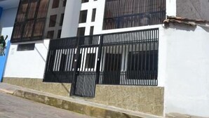 Ein zweistöckiges Gebäude mit weißer Fassade, großen Fenstern und einem schwarzen Metallzaun davor.