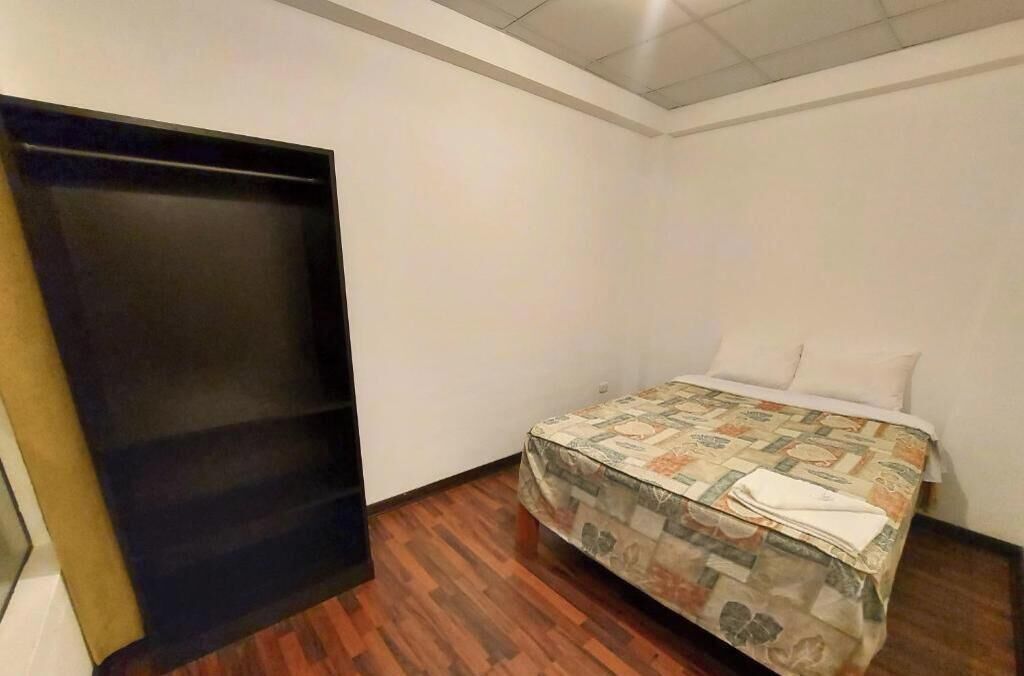 Una habitación pequeña con cama, suelo de madera y armario.