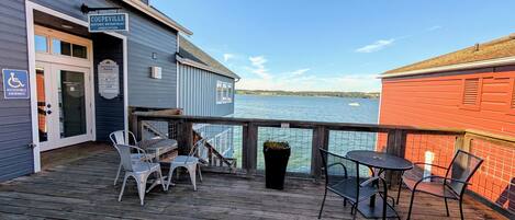 A wooden deck with outdoor seating, a sign for the 'Coupeville Historic Waterfront Association,' and a view of the water.