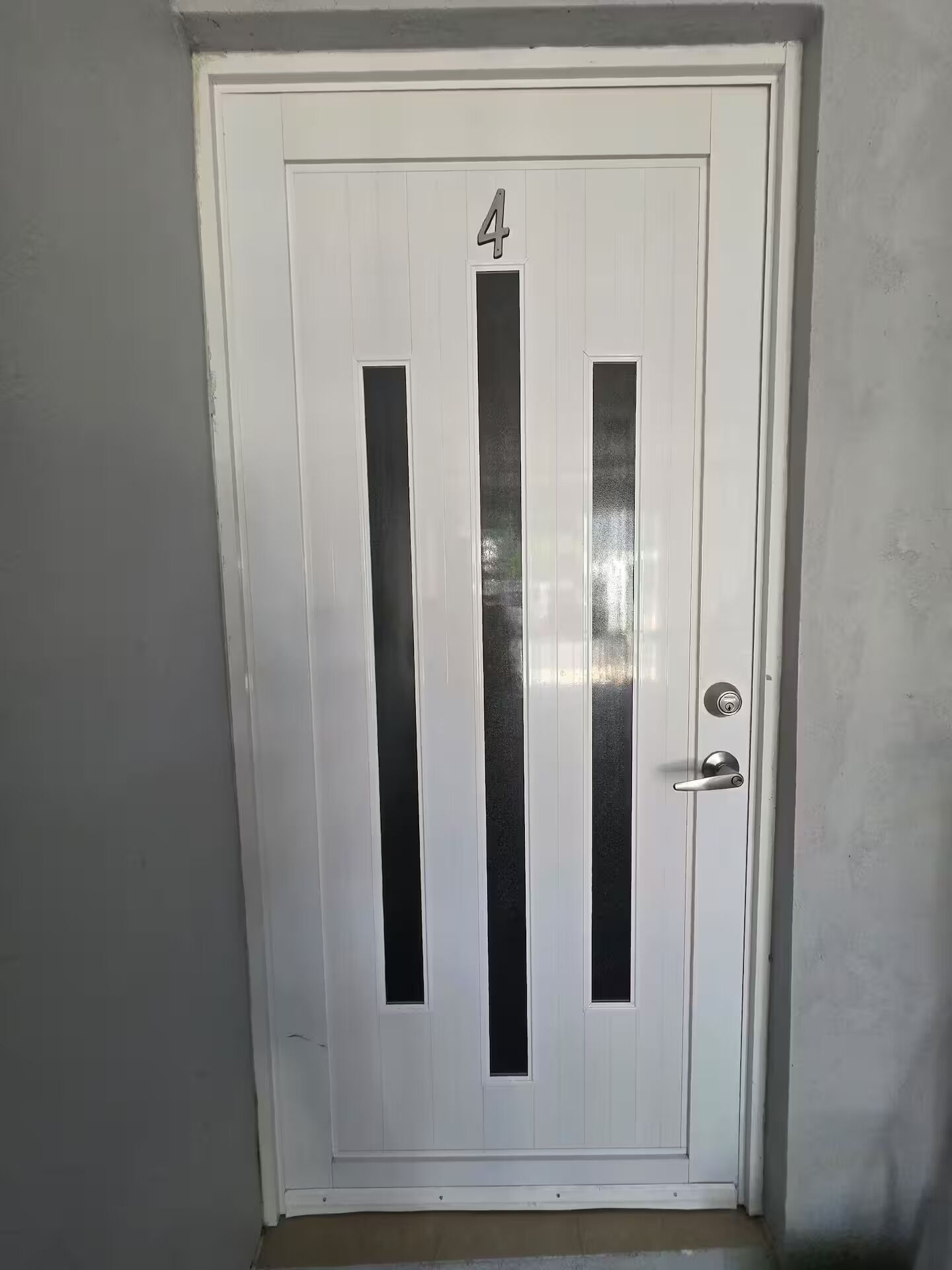 Une porte blanche portant le numéro 4, avec un trou de serrure et une poignée de porte.