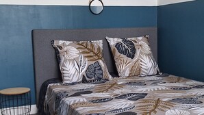 Een slaapkamer met een bed, twee spiegels aan de muur en een klein rond tafeltje.