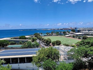 A coastal view with a sports field, solar panels, and a clear blue sky. - Amazing Apartment Near Papeete (Papeete)