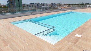 Een dakterraszwembad met een helder uitzicht op de omliggende gebouwen en een stadsachtergrond.
