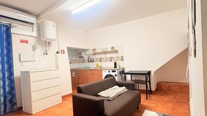 A compact living space with a kitchenette, a sofa, a dining table, and a patterned rug. - Apartment 'O Meu Cantinho' with Wi-Fi and Air Conditioning (Elvas)