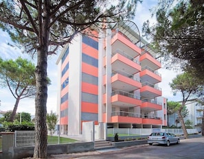 A multi-story building with balconies, a gated entrance, and a parked car. - Residence Rosa die Venti Two-room apartment Bilo for 5 people (Bibione)