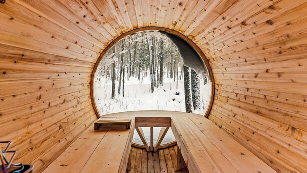 Eine Holzhütte mit einem Rundfenster, einer Holzbank und einem Tisch.