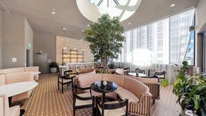 A modern lounge area with seating arrangements, a central plant, and large windows providing natural light. - Modern Condo in the Heart of Miami - Gym (Miami)