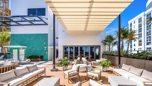 A rooftop lounge with outdoor seating, a glass entrance, and a view of the city. - Modern Condo in the Heart of Miami - Gym (Miami)