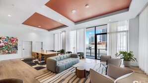 A modern living room with a sofa, chairs, a dining table, and a large window with a city view. - Modern Condo in the Heart of Miami - Gym (Miami)