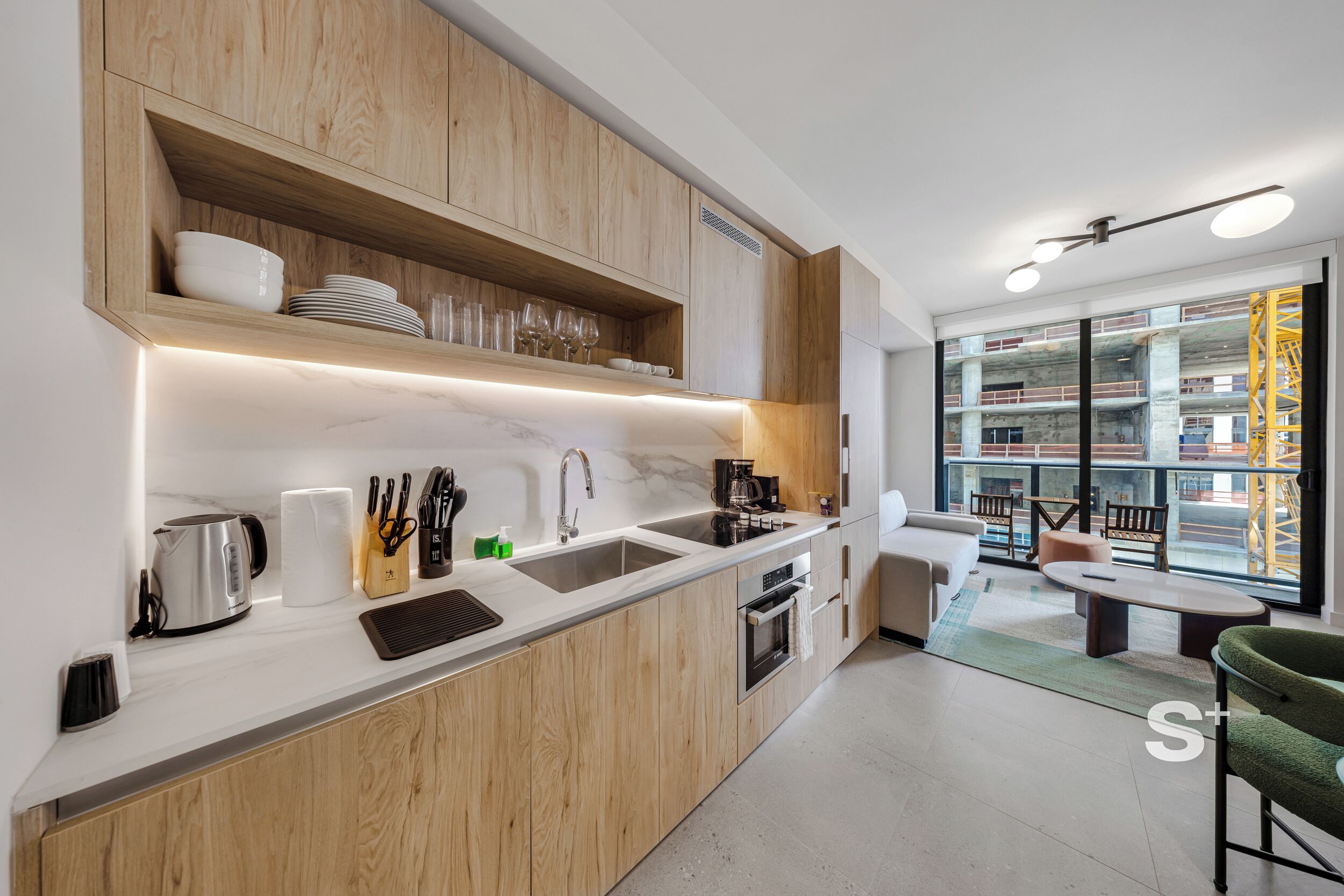 A modern kitchen with wooden cabinets, a marble countertop, and a built-in oven.