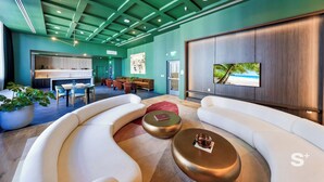 A modern lobby with a curved white sofa, a large flat-screen TV, and a kitchen area in the background. - Modern Condo in the Heart of Miami - Gym (Miami)
