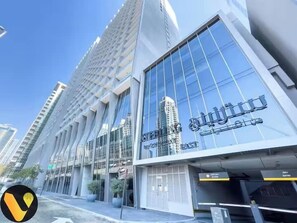 A modern building with large glass windows and a sign in Arabic. - Vogue | Sterling Downtown near Dubai Mall | Burj Khalifa (Dubai)