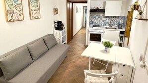 A compact living space with a sofa, a dining table with chairs, a kitchen area, and a small seating area with a coffee machine. - In the heart of Palermo, cozy apartment in the Historic Center. (Palermo)