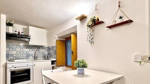 A compact kitchen with white cabinets, a patterned backsplash, and a white dining table with chairs. - In the heart of Palermo, cozy apartment in the Historic Center. (Palermo)
